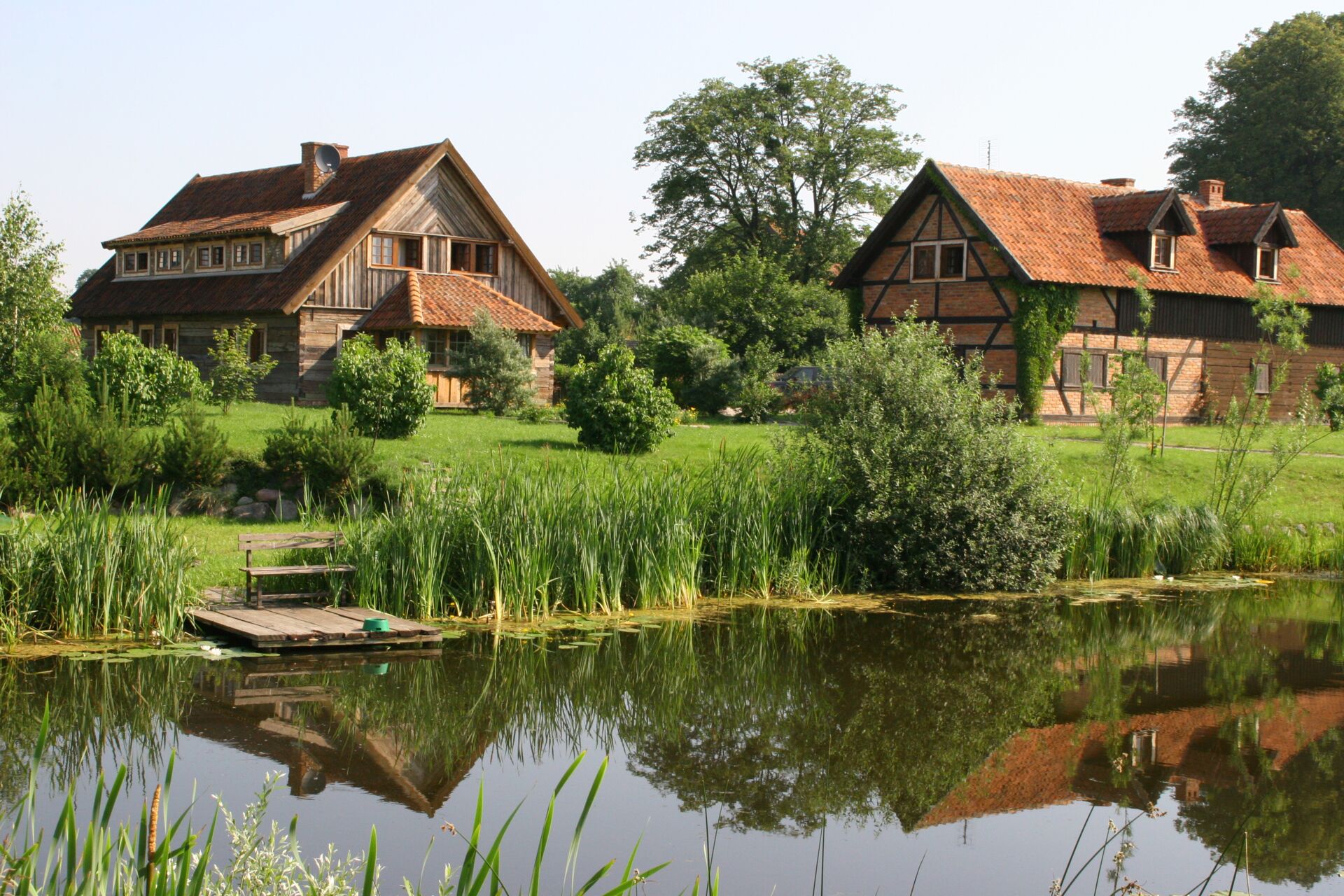 Ein idyllischer See in Masuren mit traditionellen Häusern am Ufer im Hintergrund